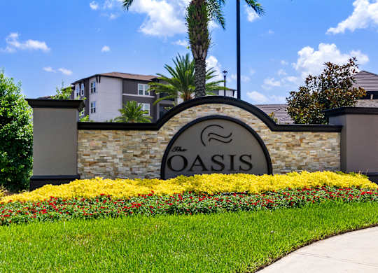 The Oasis sign is surrounded by a flower bed.
