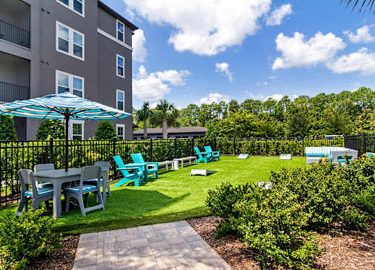 A patio with a table and chairs is surrounded by a black fence.