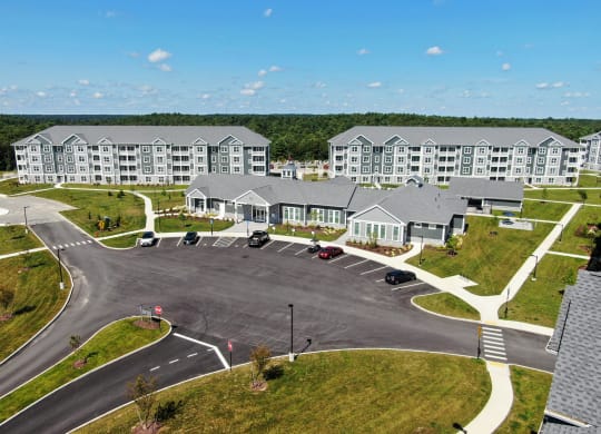 an aerial view of an apartment complex with a road and parking lot  at The Oasis at Plymouth, Plymouth, MA