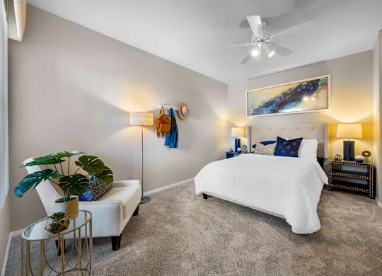 A bedroom with a white bed and a painting on the wall.