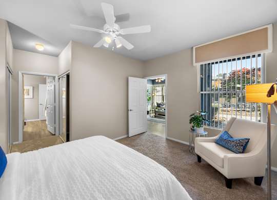 A bedroom with a large bed and a white ceiling fan.