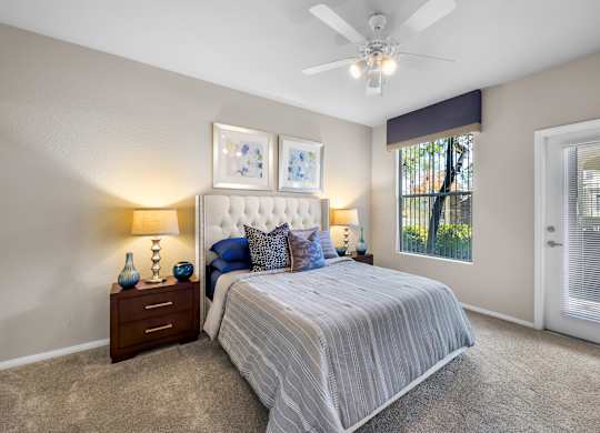 A bedroom with a large bed, a ceiling fan, and two nightstands with lamps.