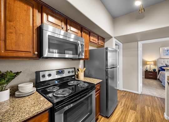 A kitchen with a black stove top oven and a black microwave above it.