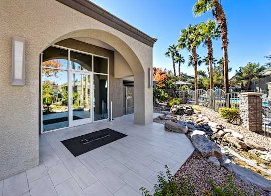 A modern house entrance with a stone wall and a black doormat.