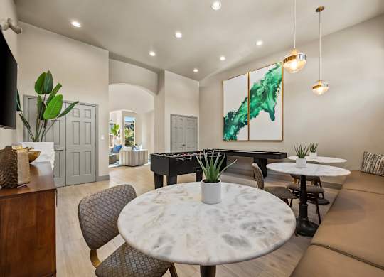 A modern living room with a large painting, a round marble table, and a brown leather sofa.