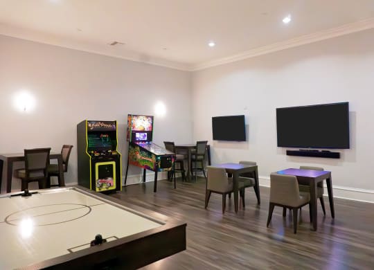 a living room with tables and chairs and a tv and games on the wall at The Oasis at Moss Park, Florida