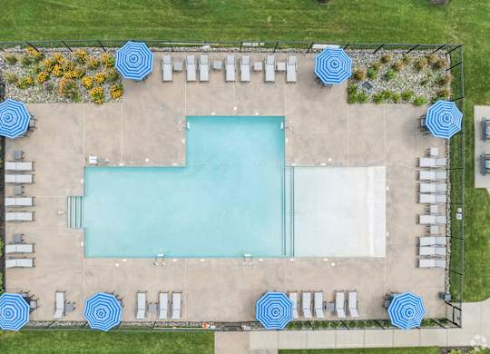 A large rectangular pool surrounded by blue umbrellas and lounge chairs.