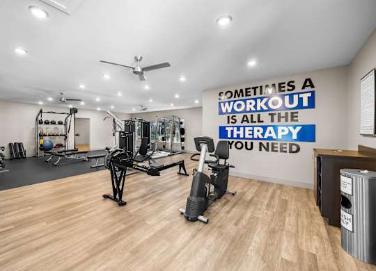 A gym with a wall that says "Sometimes a workout is all the therapy you need".