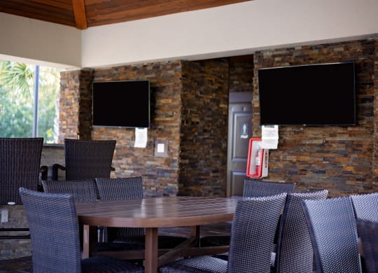 a dining area with a table and chairs and televisions on the wall at The Oasis at Moss Park, Orlando
