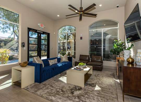 A living room with a blue couch and a ceiling fan.