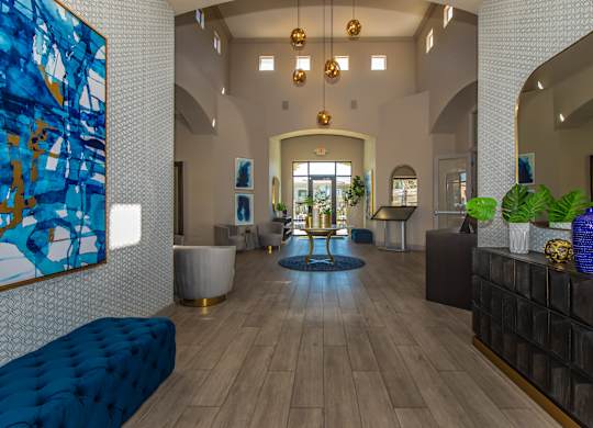 A large blue and gold abstract painting hangs on a white wall in a spacious lobby.