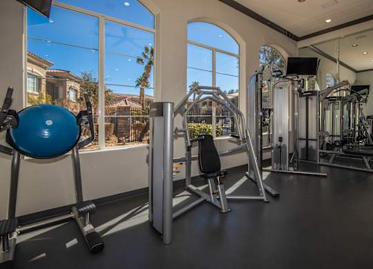 A gym with a blue ball and a mirror on the wall.