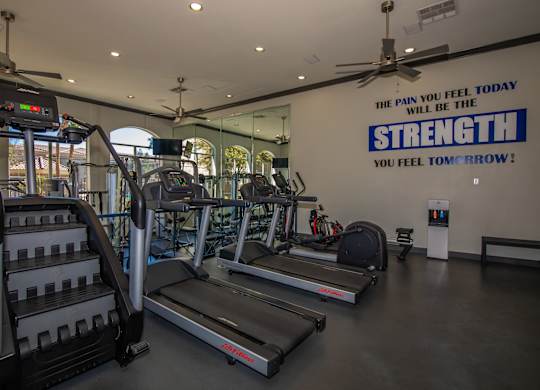 A gym with treadmills and a sign that says "The pain you feel today will be the strength you feel tomorrow!"