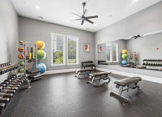 A spacious home gym with a variety of equipment including a bench press, dumbbells, and a rowing machine.