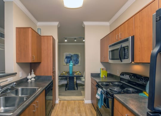 a kitchen with wooden cabinets and stainless steel appliances and a dining room with a table at Loreto & Palacio Apartments, Nevada 89149