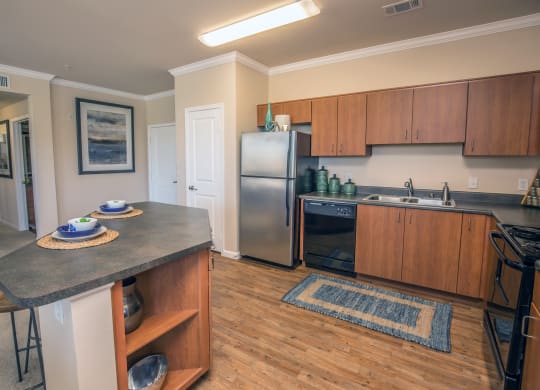 a kitchen with stainless steel appliances and wooden cabinets and a granite counter top at Loreto & Palacio Apartments, Las Vegas
