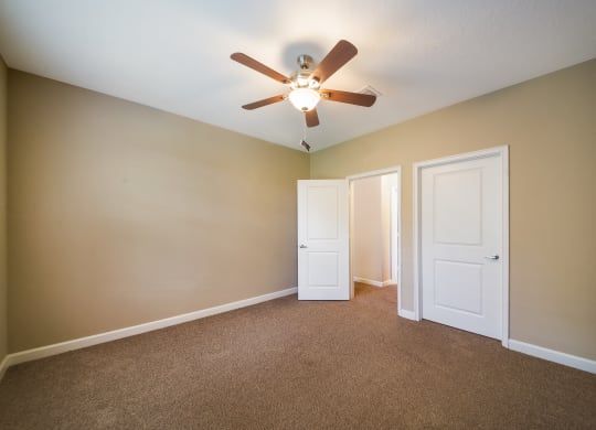 an empty living room with a ceiling fan and two doors at The Oasis at Highwoods Preserve, Tampa, FL, 33647