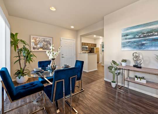 A dining room with a glass table and blue chairs.