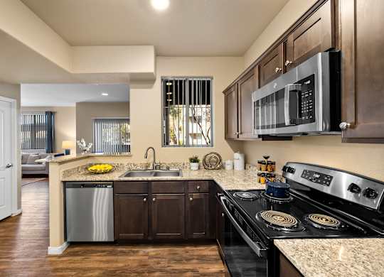 A modern kitchen with dark wood cabinets and stainless steel appliances.