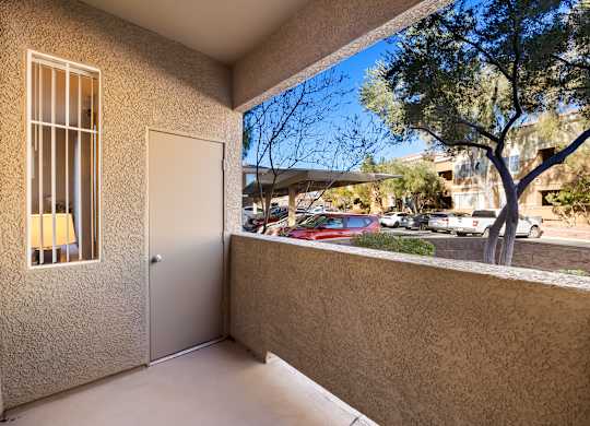 A balcony with a view of a parking lot and trees.