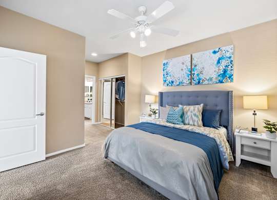 A bedroom with a bed, nightstand, and ceiling fan.
