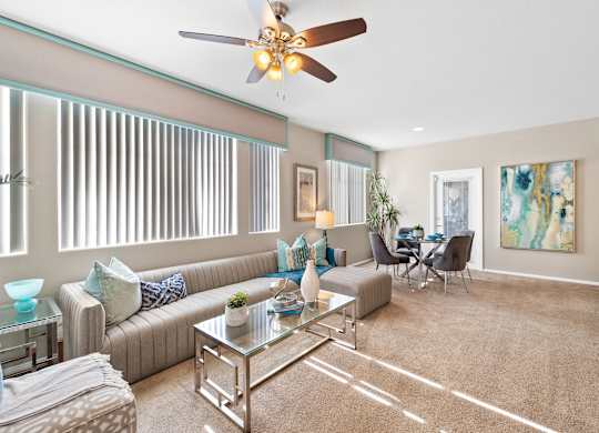 A living room with a couch, chairs, and a ceiling fan.