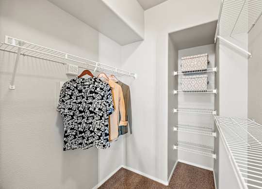 A white closet with clothes hanging and shelves.