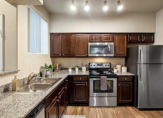 A modern kitchen with dark wood cabinets and stainless steel appliances.