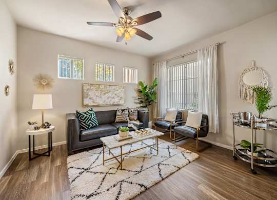 A living room with a grey couch, a coffee table, a ceiling fan, and a rug.