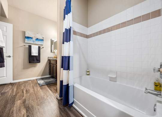 A bathroom with a white tub and a blue and white shower curtain.
