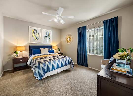 A bedroom with a bed, nightstands, and a ceiling fan.