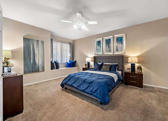 A bedroom with a bed, nightstands, and pictures on the wall.