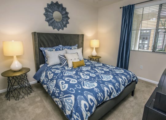 a bedroom with a bed with blue and white bedding and a window at Loreto & Palacio Apartments, Las Vegas, NV 89149
