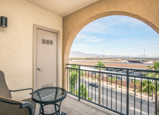 a balcony with a chair and a table and a door overlooking the street at Loreto & Palacio Apartments, Las Vegas