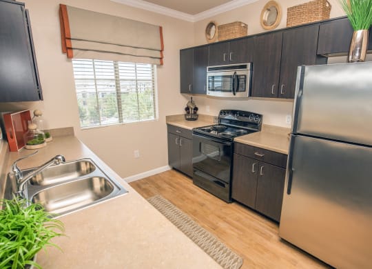 Kitchen with dark wood cabinet and a stainless refrigerator at Loreto & Palacio Apartments, Las Vegas, Nevada