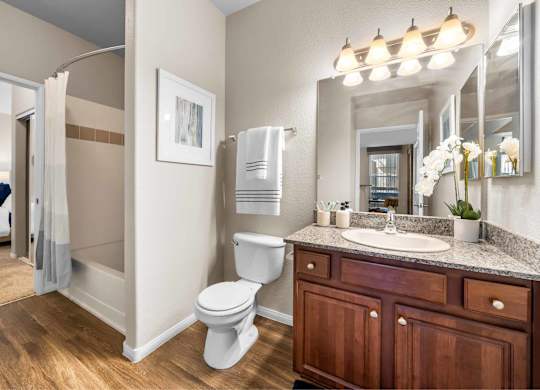 A bathroom with a toilet, sink, and mirror.at The Equestrian by Picerne, Henderson