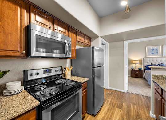 A kitchen with a black stove top oven and a black microwave above it.at The Equestrian by Picerne, Henderson, NV 89052
