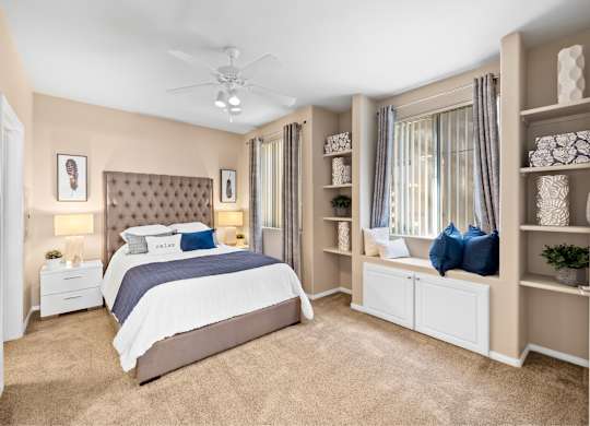 A bedroom with a large bed and a ceiling fan. at The Fairways by Picerne Apartments, Las Vegas