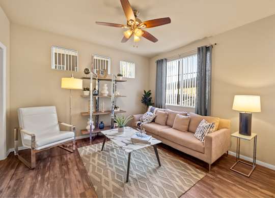 Living room with windows and casual comfortable furniture at The Fairways by Picerne Apartments, Las Vegas, NV