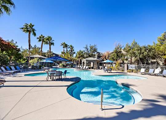 A large swimming pool surrounded by palm trees and lounge chairs.
