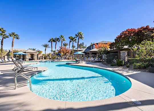A large swimming pool surrounded by palm trees and lounge chairs.