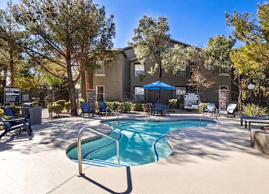 A pool surrounded by trees and chairs with a sign that says