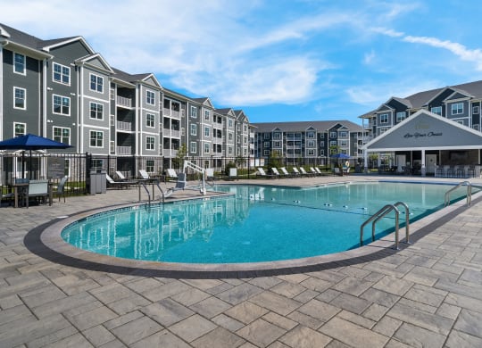a swimming pool with an apartment building in the background at The Oasis at Plymouth, Plymouth, MA, 02360