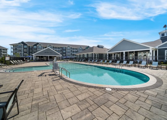 a resort style pool with chairs and a building in the background at The Oasis at Plymouth, Massachusetts