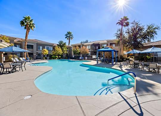 A sunny day at the pool with palm trees and apartment buildings in the background.