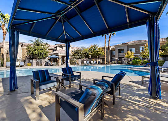 A poolside area with blue umbrellas and lounge chairs.