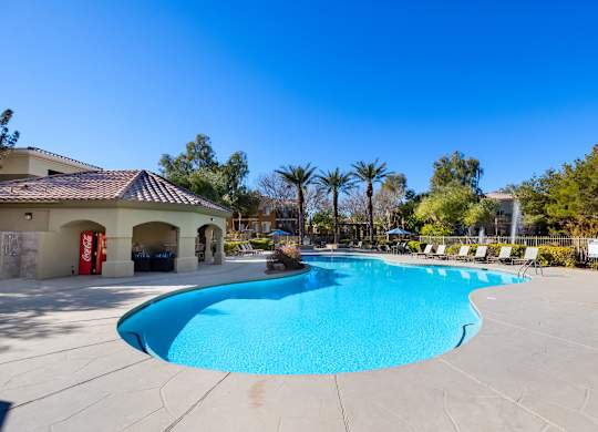 A large outdoor swimming pool with a sun lounger chairs around it.