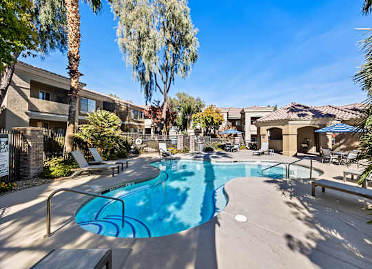 A swimming pool surrounded by palm trees and apartment buildings.