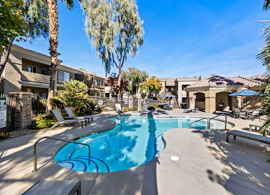 A swimming pool surrounded by palm trees and apartment buildings.
