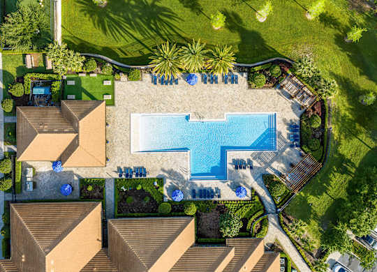 A swimming pool surrounded by a grassy area and a few trees.